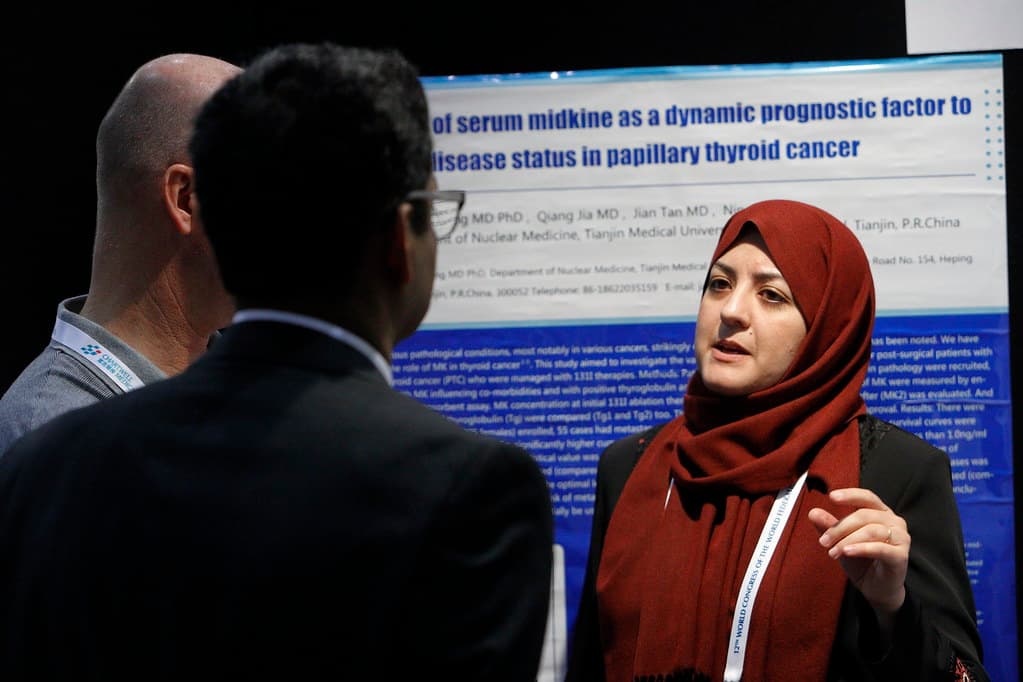 A researcher presenting her scientific poster to two delegates at the World Congress.