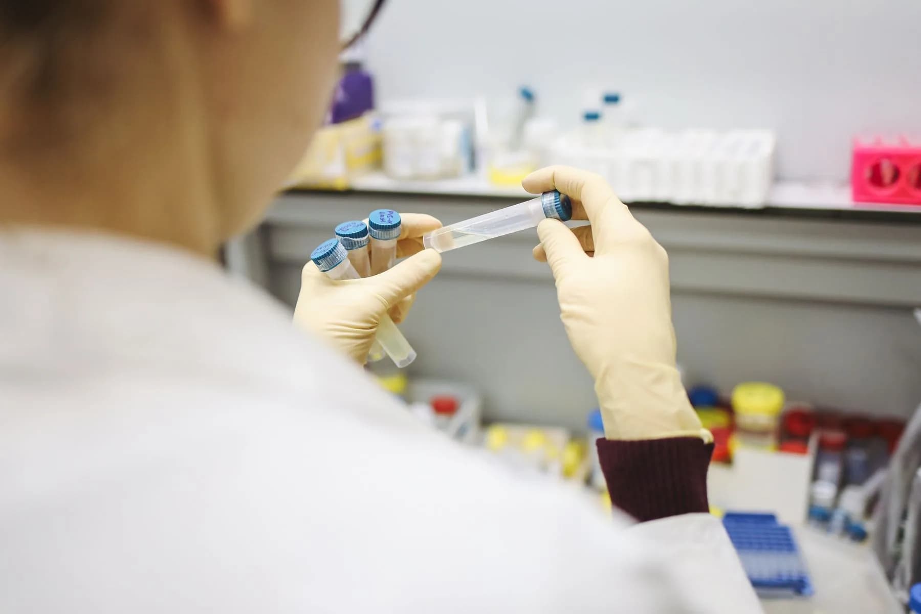 A researcher in gloves examining labelled sample vials of a radioligand preparation at a laboratory bench.