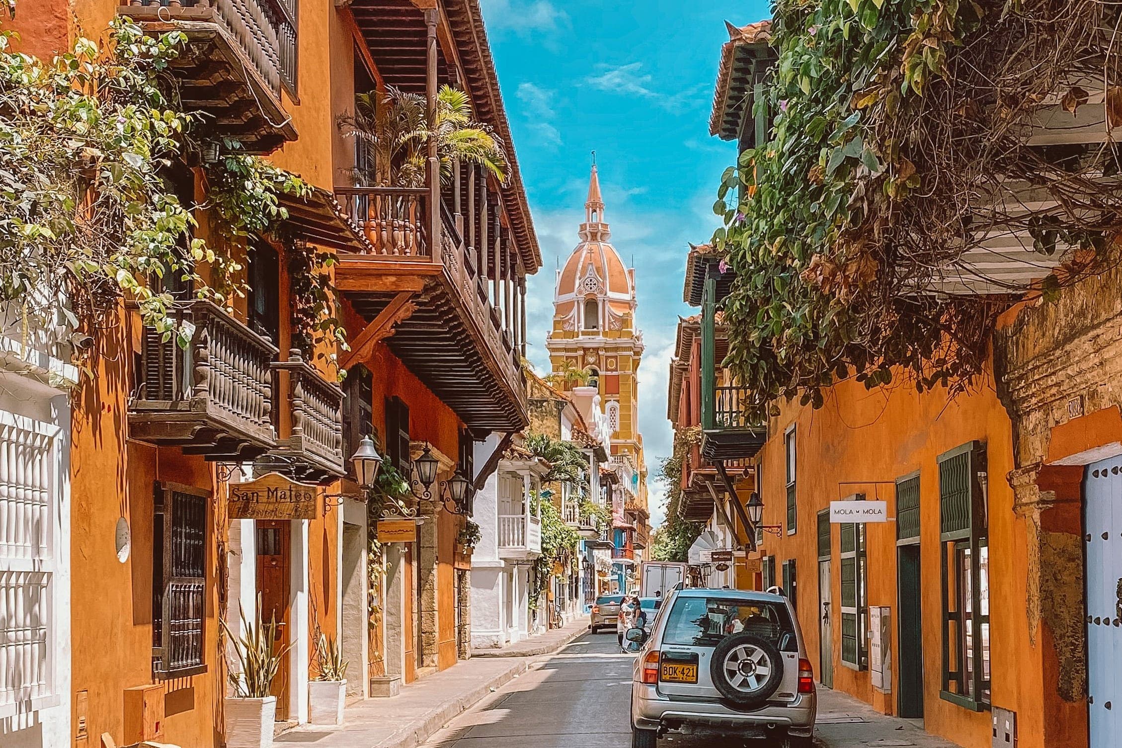 A street in Cartagena's walled city, wooden balconies on either side and the cathedral's dome at the end of the road.