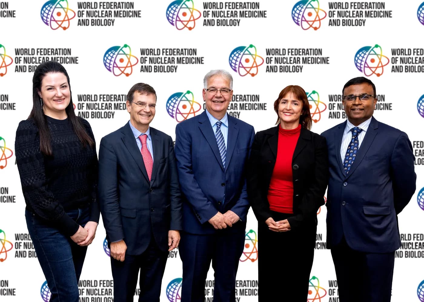 Five members of the WFNMB executive standing together in front of the Federation’s banner.