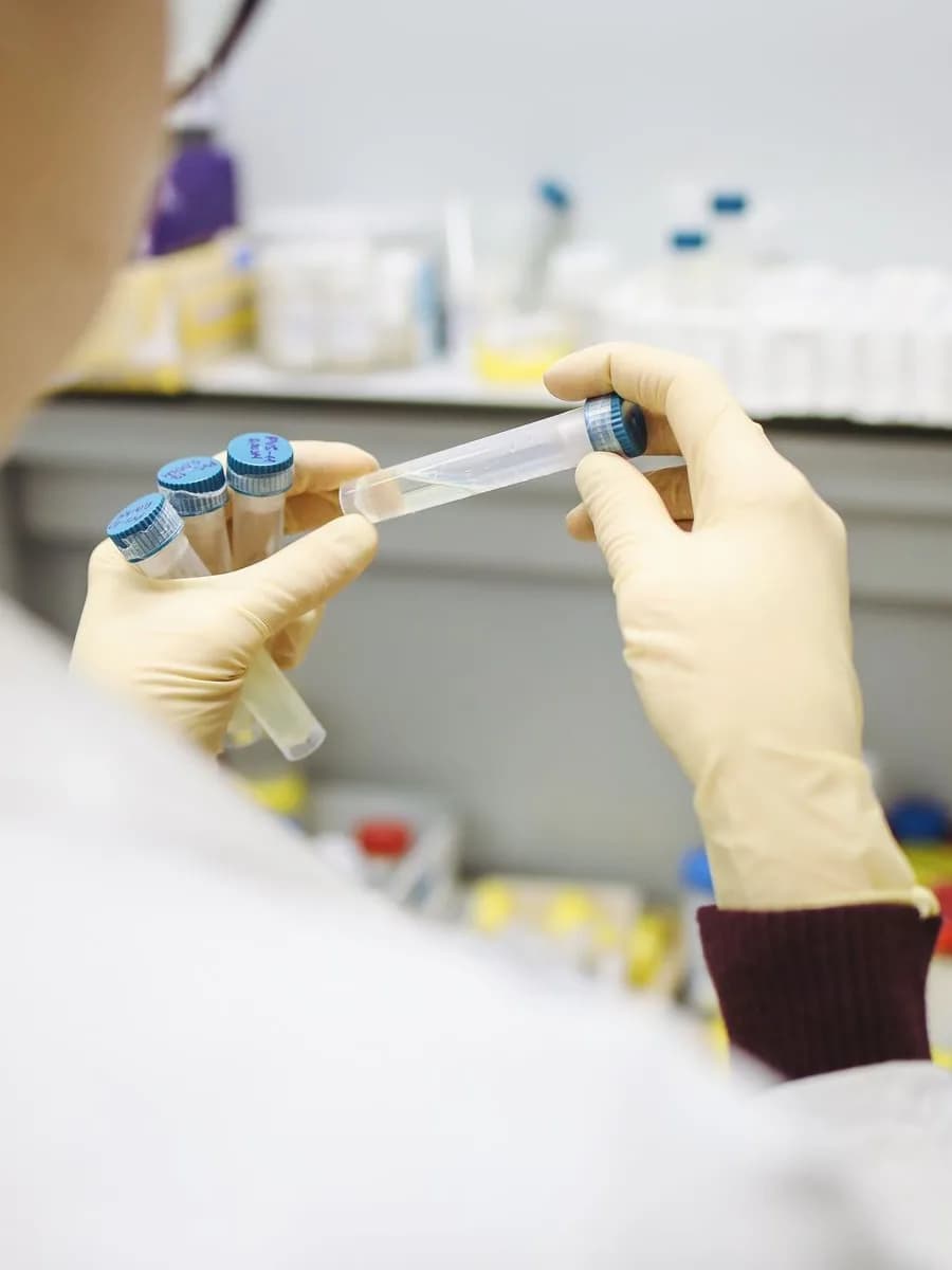 A researcher’s gloved hands holding labelled sample vials of a radioligand preparation at a laboratory bench.
