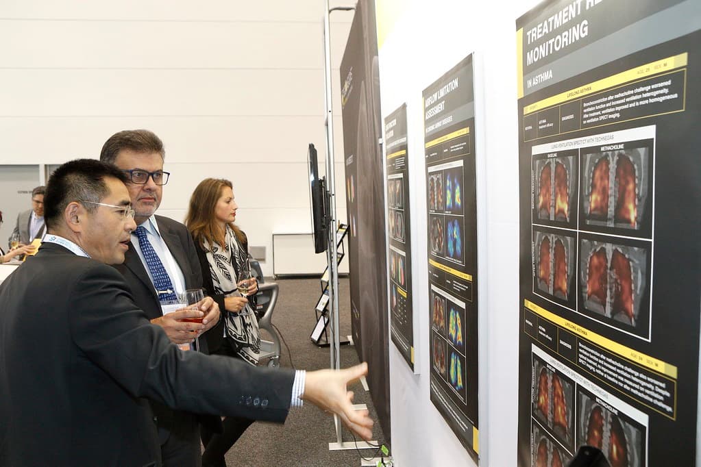 Delegates studying scientific posters of PET and molecular-imaging studies at the World Congress, one pointing to the imaging data.