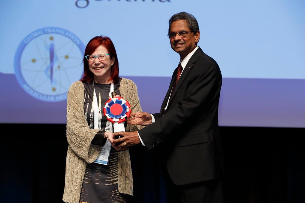 A delegate receiving an award on stage at the World Congress, before a backdrop reading “global translation of molecular medicine”.