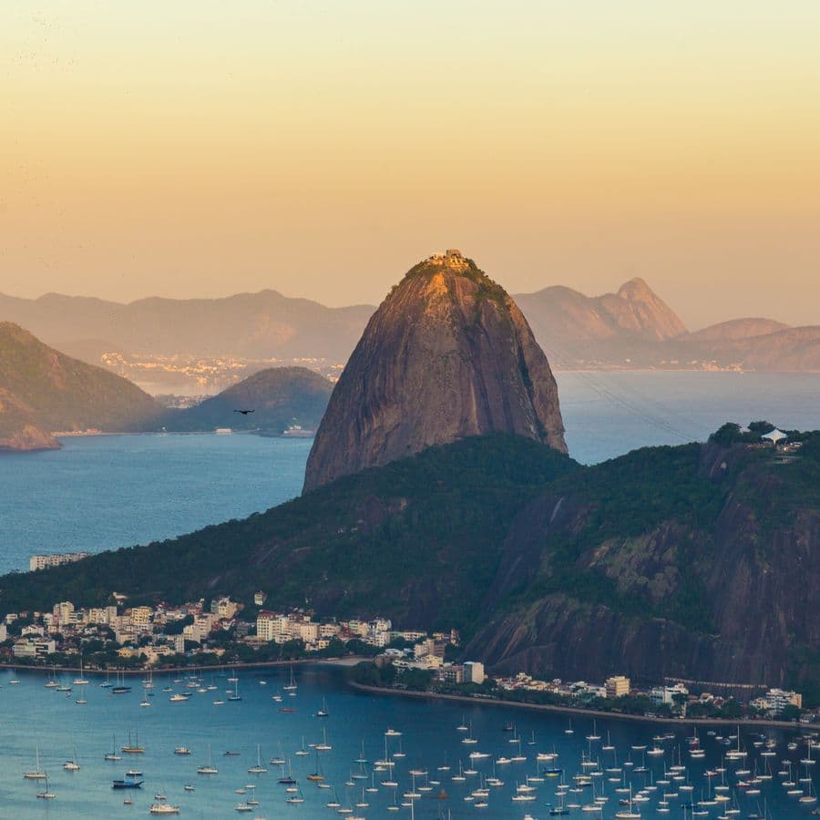 Sugarloaf Mountain over the bay in Rio de Janeiro at sunset, boats on the water.